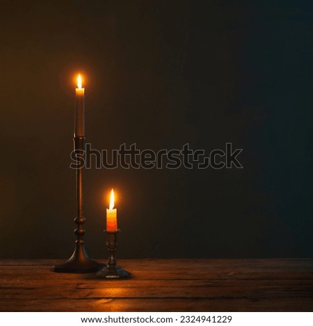 burning candles in vintage candlesticks on dark background Royalty-Free Stock Photo #2324941229