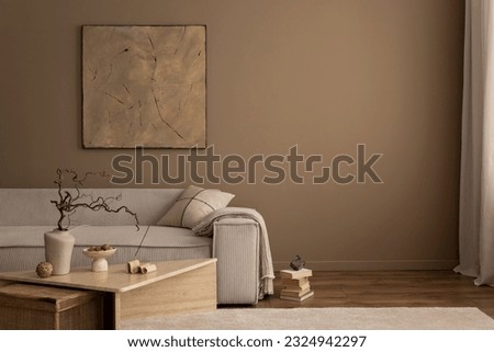 Warm and cozy living room interior with mock up poster frame, painting, beige sofa, travertine coffee table, slippers, bowl with nuts, plaid, pillow and personal accessories. Home decor. Template. Royalty-Free Stock Photo #2324942297