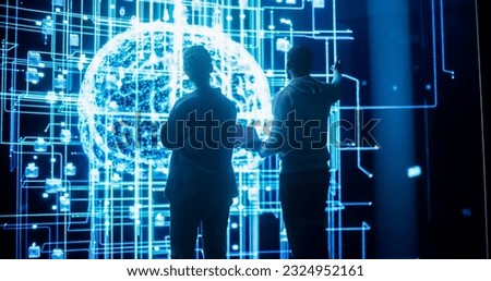 Back View of Two Diverse Colleagues Looking at a Big Screen with Neural Network 3D Visualisation. Professional Computer Data Scientists Discussing and Working on Monitoring Private Information Royalty-Free Stock Photo #2324952161