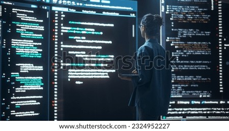Shot of Female Programmer Working in a Monitoring Control Room, Surrounded by Big Screens Displaying Lines of Programming Language Code. Portrait of Woman Creating a Software, Coding Royalty-Free Stock Photo #2324952227