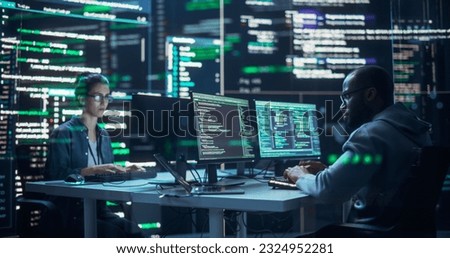 Portrait of Two Diverse Developers Working on Computers, Typing Lines of Code that Appear on Big Screens Surrounding Them. Male and Female Programmers Creating Innovative Software, Fixing Bugs. Royalty-Free Stock Photo #2324952281