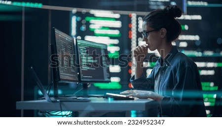 Female Developer Thinking and Typing on Computer, Surrounded by Big Screens Showing Coding Language. Focused Programmer Creating Software, Running Coding Tests. Futuristic Concept of Programming Royalty-Free Stock Photo #2324952347