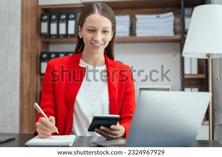 Business woman take notes and use the calculator with calculations about the expenses at the office. Royalty-Free Stock Photo #2324967929