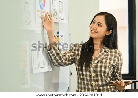 Shot of beautiful project manager presenting sketch designs, application template layout framework on whiteboard during meeting