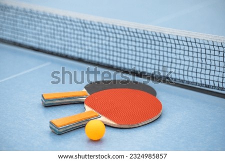 Table tennis. Blue ping pong table. Ping pong rackets and ball. The concept of sport and healthy lifestyle. Royalty-Free Stock Photo #2324985857