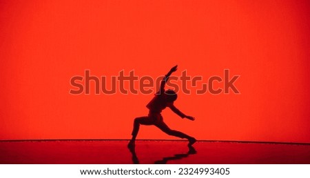 Male Dancer in White Clothes Unleashing an Energetic Fusion of Styles with Powerful Modern Dance Choreography, Swift Turns and Athletic Grace, Dancing in Front of an Solid Red Digital Screen Royalty-Free Stock Photo #2324993405
