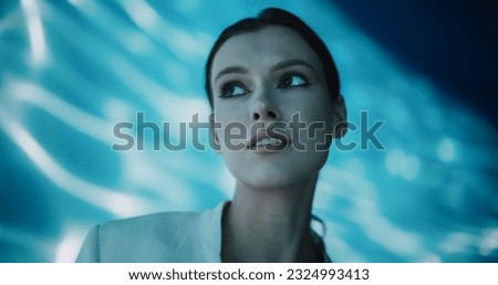 Cinematic Portrait with a Stylish Elegant Model in White Clothes Standing Inside a Abstract Underwater Room with Abstract Art Background. Young Female in a Beautiful Mystical Place