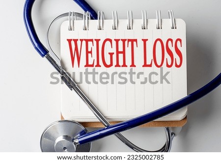 WEIGHT LOSS word on a notebook with medical equipment on background