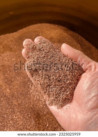 Right hand holding recycled copper granules recovered from scrap cable. High quality photo