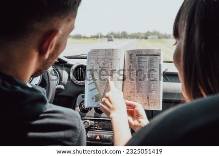 two couple looking their way in the map in the car