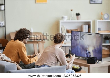 Side view portrait of young couple playing video games on TV at home