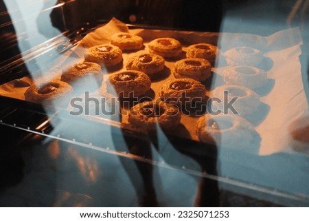 Image of homemade freshly baked cupcakes in a closed electric oven. Lifestyle, baking and spending time at home concept.