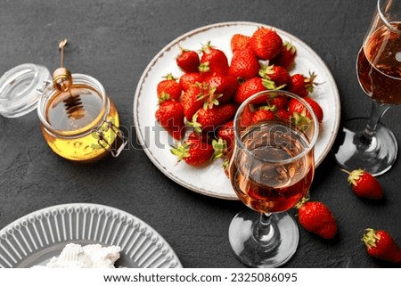 Plate with fresh strawberry and glass of wine on black background