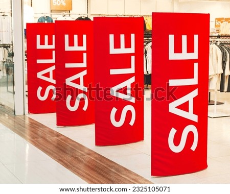 White inscription Sale at the entrance to the clothing store. Red sale sign on anti-theft gate sensor at entrance to clothing store. Store sale, discount, black friday. Proposal of seasonal discounts Royalty-Free Stock Photo #2325105071