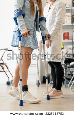 Young woman trying out crutches in a store Royalty-Free Stock Photo #2325118753