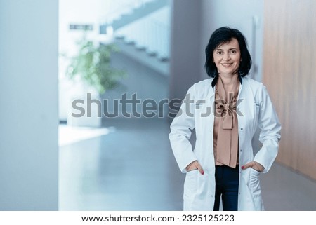 Portrait of positive female doctor psychologist in lab white coat in lobby of in modern hospital clinic office. Medicine, profession and healthcare concept. Royalty-Free Stock Photo #2325125223