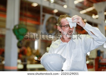 boss manager engineer with helmet tired in construction factory heavy industry . tired senior worker taking break and use tissue paper wiping sweat from forehead heat wave high temperature. Royalty-Free Stock Photo #2325129051