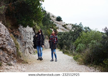 Couple of hikers with backpack walking on mountain road observing all around them, young hikers walking on mountain trail looking for beautiful tree grow on the rock, couple of hikers looking at rocks