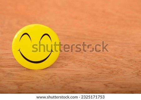 Yellow happy face with smile isolated on a wooden background.