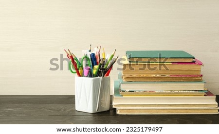 School supplies, pens, pencils, felt-tip pens, books and textbooks, stand on a table on a wooden background.  The concept of back to school, learning at school and college.  Background picture. Royalty-Free Stock Photo #2325179497