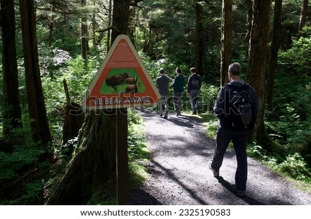 a warning sign about bears in the area is set up at the beginning of the trail where people are starting to hike