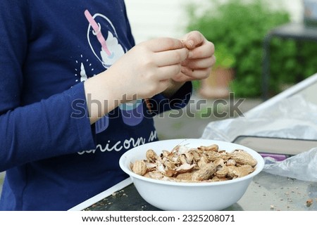 young girl shelling peanuts into a plate in the backyard