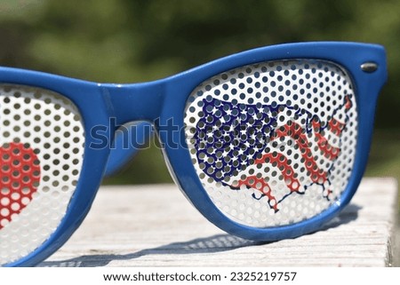 Patriotic sunglasses. I love United States, USA, US, America.  Sitting on a porch railing with a forested, out of focus background. Focus on forefront.