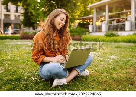 Smiling young woman with a laptop working or studying online outdoor. Concept for education, business, blog or freelance. Royalty-Free Stock Photo #2325224865