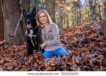 A gorgeous blonde model enjoys the outdoor fall weather with her dog in the park