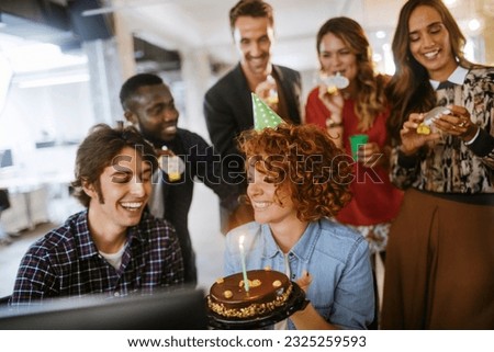 Group of young people celebrating a birthday in the office