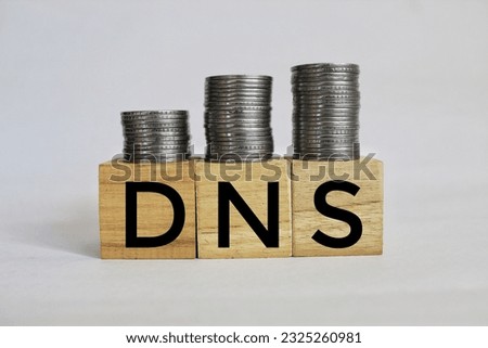 DNS text on wooden cubes with stacked coins on table. Domain name System server concept.