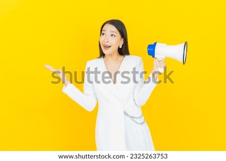 Portrait beautiful young asian woman smile with megaphone on yellow color background