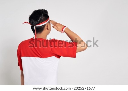 Back view young Asian man standing confidently giving a salute and respectful gestures isolated over white background. Celebrate Indonesia independence day on 17 August Royalty-Free Stock Photo #2325271677