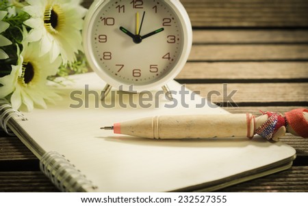 White old clock and blank paper with pen, on wooden table vintage Style.