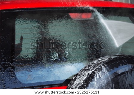 High-pressure washing red car outdoors,car wash