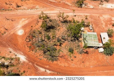 Aerial view of a miners tin shack surrounded by red dirt and wheel tracks