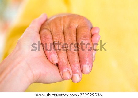 Close up photo of elderly woman hand hold by young carer hand