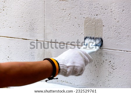 Painting white color on cement wall by paintbrush. Royalty-Free Stock Photo #232529761