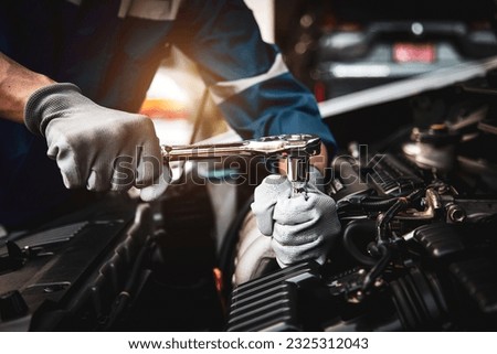 Car care maintenance and servicing, Hand technician auto mechanic using the wrench to fix car or repairing change spare part engine problem and insurance service support the range of car check. Royalty-Free Stock Photo #2325312043