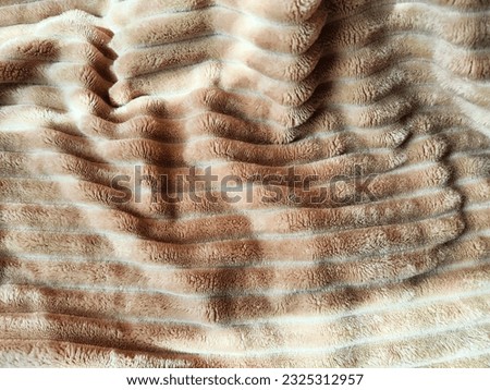 Closeup soft, fluffy sleeping beige blanket or plaid. Crumpled fabric. Abstract background, texture with frame. Partial focus