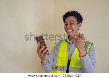 Young construction guys wear the wearpack pick up the phone and happiness pose. The photo is suitable to use for engineer poster and safety content media.
