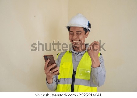 Young construction guys wear the wearpack pick up the phone and happiness pose. The photo is suitable to use for engineer poster and safety content media.