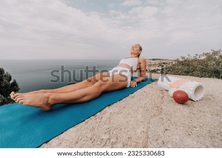 Woman sea pilates. Sporty, middle-aged woman practicing pilates in park near the sea. trains on a yoga mat and exudes a happy and active demeanor. healthy lifestyle through exercise and meditation.