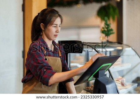 Portrait owner cafe bakery standing behind counter inside shop, close bakery, charging at store's cash register it's also machine that can accept orders in front counter, was focusing on that machine.