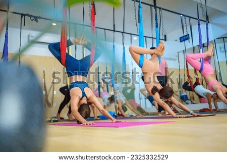 woman in sportswear wrapping leg around hammock and swinging,shot fit female practicing fly yoga in class studio.Close-up in 4K, UHD