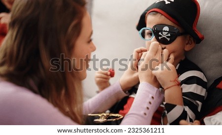 Adorable boy and woman having halloween party drawing moustache at home