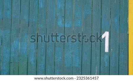 The number one is written in white paint on a green wall with a yellow stripe, 1