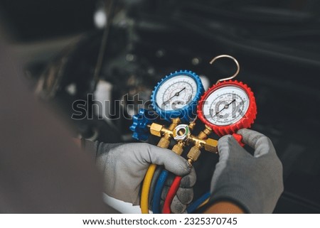 Hand of car mechanic technician use meter to check car air conditioner system heat problem and fix repairing and filling air refrigerant. Royalty-Free Stock Photo #2325370745