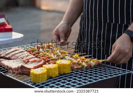 Meat and skewers ingredients for barbecue party are placed on grill to cook barbecue and make it ready for family to join barbecue party tonight.  party background image has Copy Space for text. Royalty-Free Stock Photo #2325387721