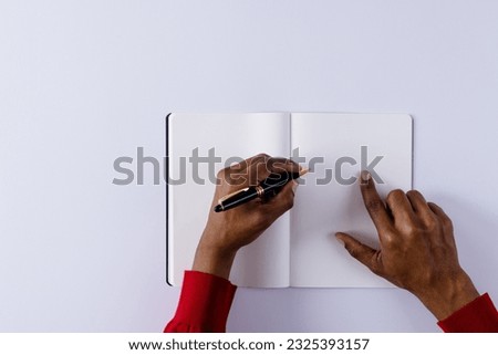 Hands of biracial man holding pen, writing in notebook with copy space on white background. Literature, writing, leisure time and books.